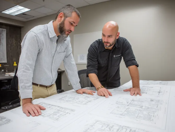 Two acoustic engineers reviewing soundproofing blueprints